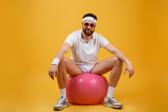 Smiling sportsman sitting on fitness ball