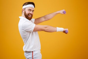 Side view of smiling sportsman with lightweight dumbbells