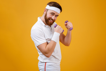 Sportsman standing sideways holding lightweight dumbbells