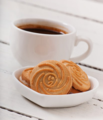Cup of coffee and delicious baked cookies on old wooden background.