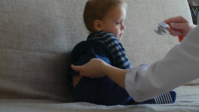Kid doctor examing happy baby boy with stethoscope.