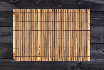 Bamboo mat for sushi on wooden background. Top view with copy space