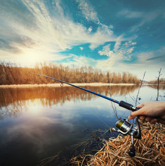 Hand with a fishing rod on lake