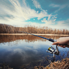 Hand with a fishing rod on lake