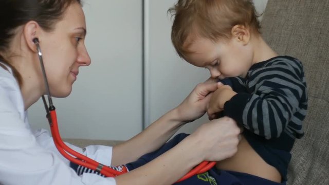 Kid doctor examing happy baby boy with stethoscope.