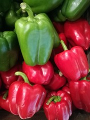 Fresh organic bell green and red pepper stand out among many pepper background in wood tray in supermarket. Heap of bell red and green pepper, Close-up