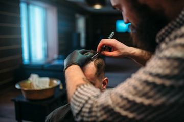 Barber shaves the hair by straight razor 