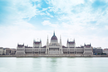 Fototapeta na wymiar Parliament building in Budapest, Hungary on a cloudy day. Building facade with reflection in water