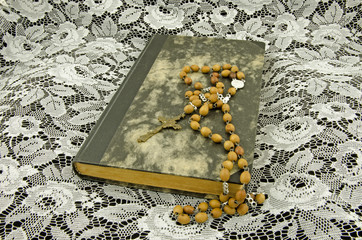 Still life with a book and a rosary on a background of lace