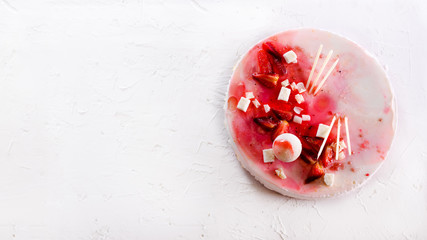 Summer strawberry mousse cake, fresh berries, coconut, and sweet decor element on top, white concrete background. Copyspace. Handmade with love.