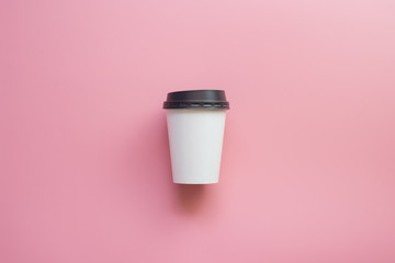 Flat lay design of hot coffee cup on pink pastel background.