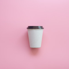 Flat lay design of hot coffee cup on pink pastel background.