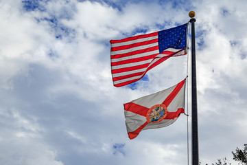 Florida state flag with american flag with cloudy sky background