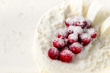 Delicious cheesecakes with cranberries, cherries, coconut flakes and white chocolate on light concrete background. Copyspace.