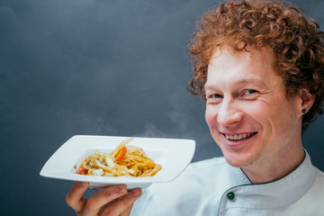 Male chef with red hair kitchen. Pasta in Thai