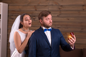 Bride in veil embracing groom with wedding rings