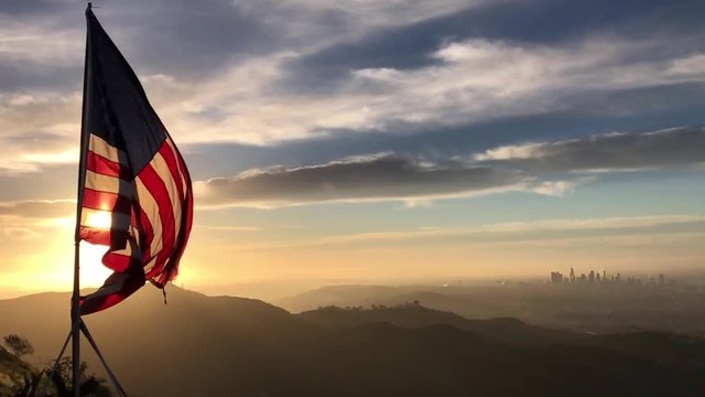 American flag flying in the wind at sunrise over the city of Los Angeles slow motion