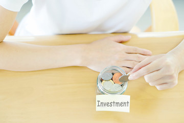 Woman hands with coins in glass jar, top view