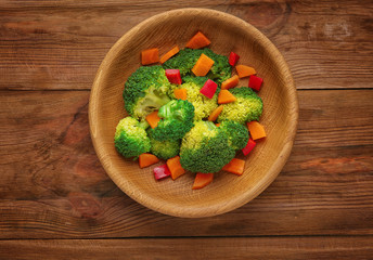 Bowl with fresh vegetables on wooden background