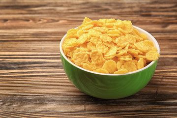 Bowl with cornflakes on wooden background