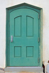 Green metal door in a white plaster wall