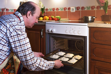 An elderly man in an apron prepares pies at home. A hospitable host prepares sweets for guests