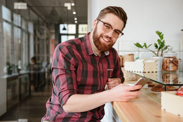 Handsome man with beard surfing internet on mobile phone