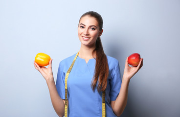 Young female nutritionist on light color background