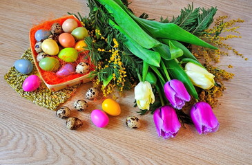 Tulips, mimosa and Easter eggs on wooden background.