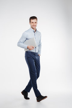 Vertical image of smiling business man walking with laptop