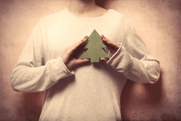 beautiful young woman hands holding fur tree shaped toy on the wonderful grey background