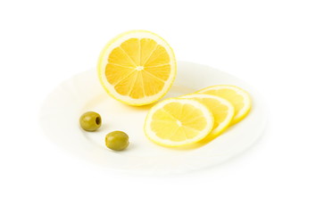 sliced lemon and two green olives in a plate, white background