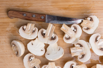 Slicing champignons on a wooden chopping board