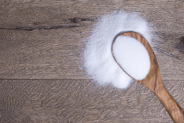 heap of sugar on rustic wooden background. Zucker auf rustikaler brauner Holzplatte mit Holzlöffel
