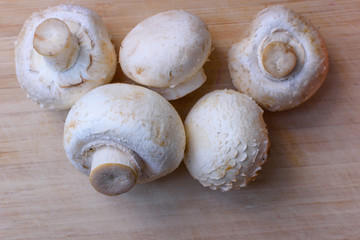 Fresh champignons on wooden kitchen cutting board