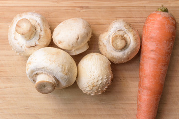 Fresh champignons on wooden kitchen cutting board