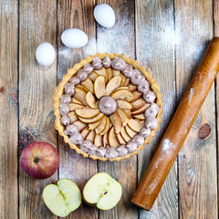 Beautiful classic apple tart with meringue. American / French pie with apples and whipped egg whites. Chocolate meringue on the cake. Baking from short pastry. Kitchen table in flour. 