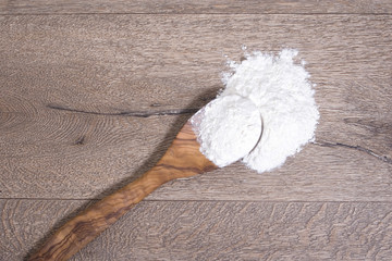 flour on wooden spoon on brown wooden background. Kochlöffel mit Mehl auf brauner Holzplatte