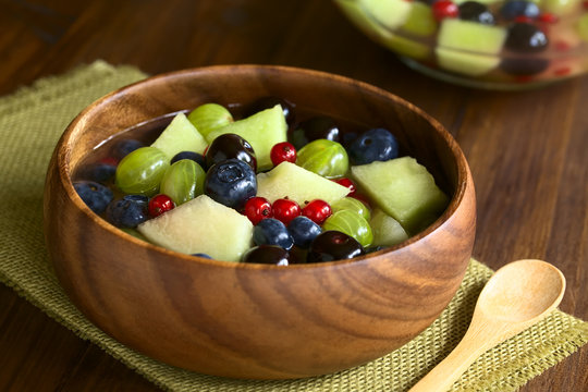 Fresh fruit salad made of cantaloupe melon, blueberry, redcurrant, gooseberry and sweet cherry, photographed with natural light (Selective Focus one third into the salad)