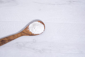 flour on wooden spoon on white wooden background. Kochlöffel mit Mehl auf weißen Holzhintergrund