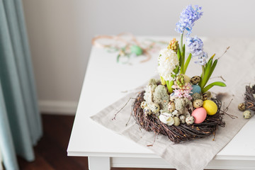 Flower arrangement in a nest with easter eggs on a white table