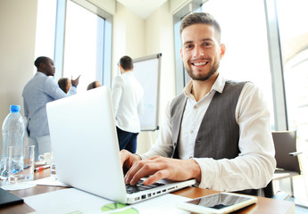 Handsome businessman working with laptop in office.