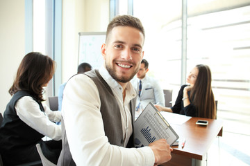 Businessman with colleagues in the background in office.