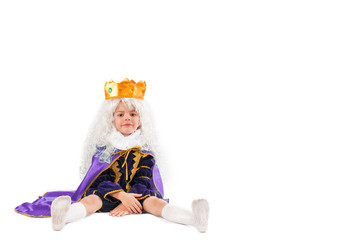 A cute little prince is sitting on the floor. White background.