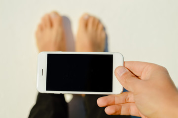 Business man hand holding using mobile smart phone on light background. Closeup view of mock up display network connection