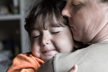 Child girl with both hands hugging his mother.
