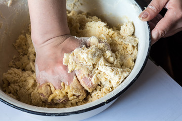 Women's hands knead the dough, make pie.
