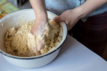 Women's hands knead the dough, make pie.
