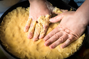 Women's hands knead the dough, make pie.
