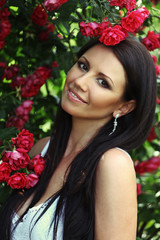 Beautiful portrait of sensual brunette young woman close to red roses